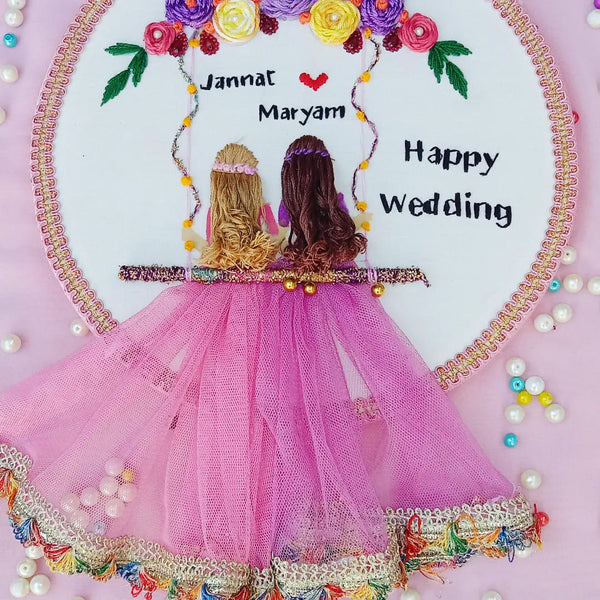 Handmade Hoop Embroidery Art titled "Jannat & Maryam: Happy Wedding Hoop Art" featuring names, wedding message, and intricate floral embroidery, displayed in a hoop.